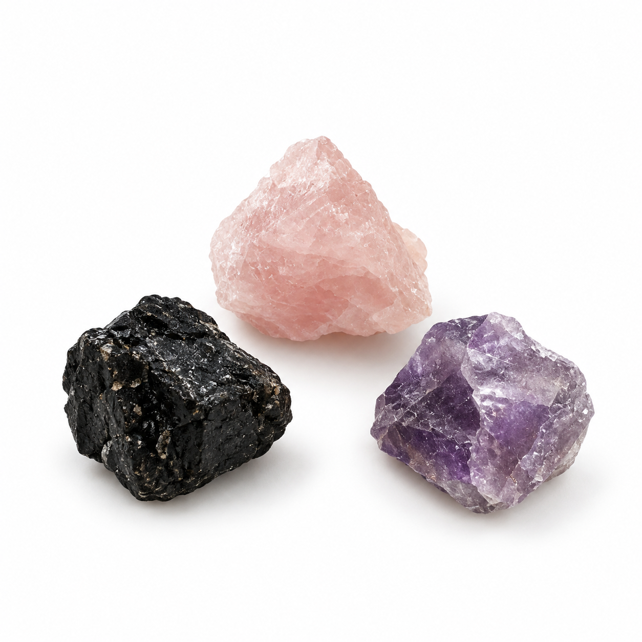Je ein roher Rosenquarz, Amethyst und Turmalin auf weißem Hintergrund